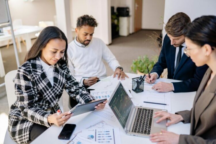 Business team engaged in planning and analysis with laptops and papers at a modern office.